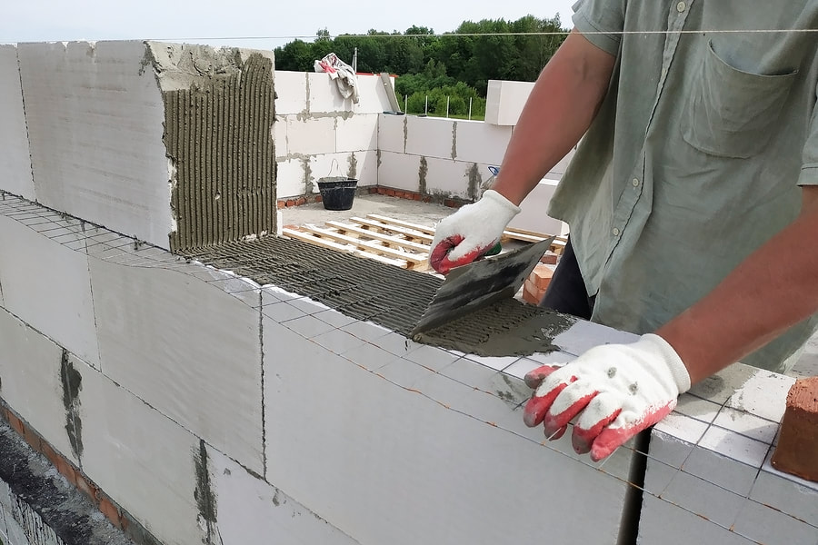 man applying cement on the concrete blocks